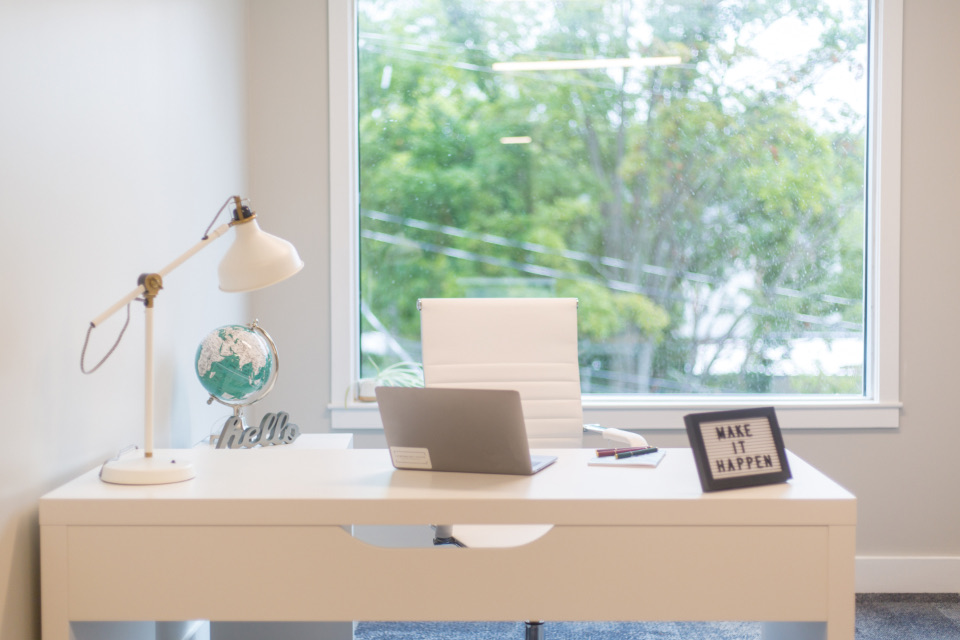 White desk in front of a window with tree views