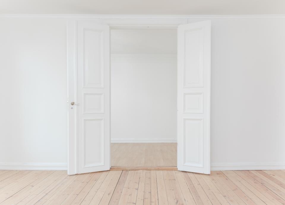 Empty white room with double doors and pale wood floor