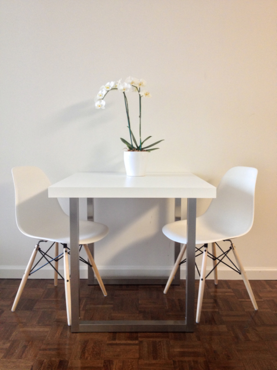 White table with two chairs and an orchid